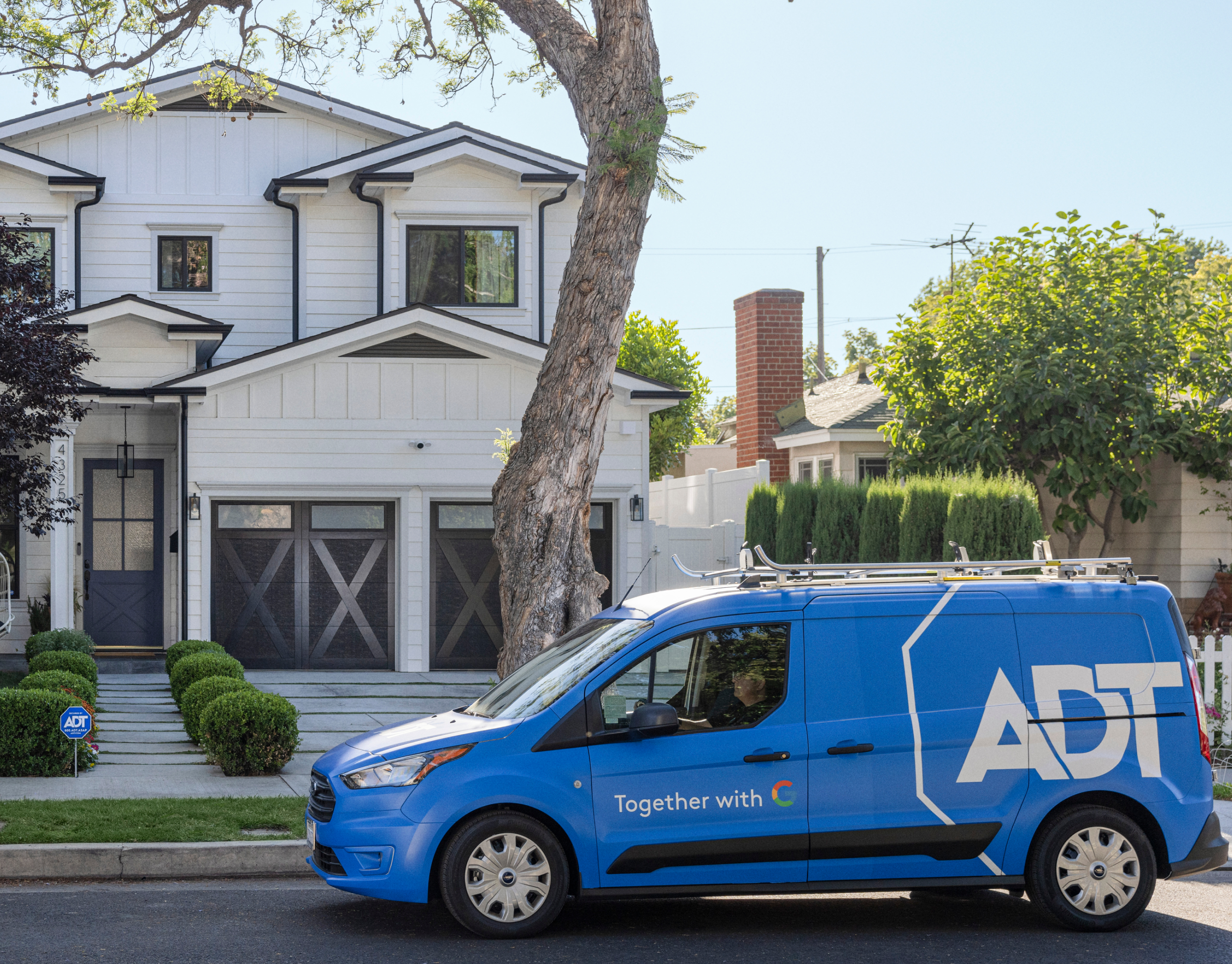 ADT van installer van parked outside of someone's house with a tree in front