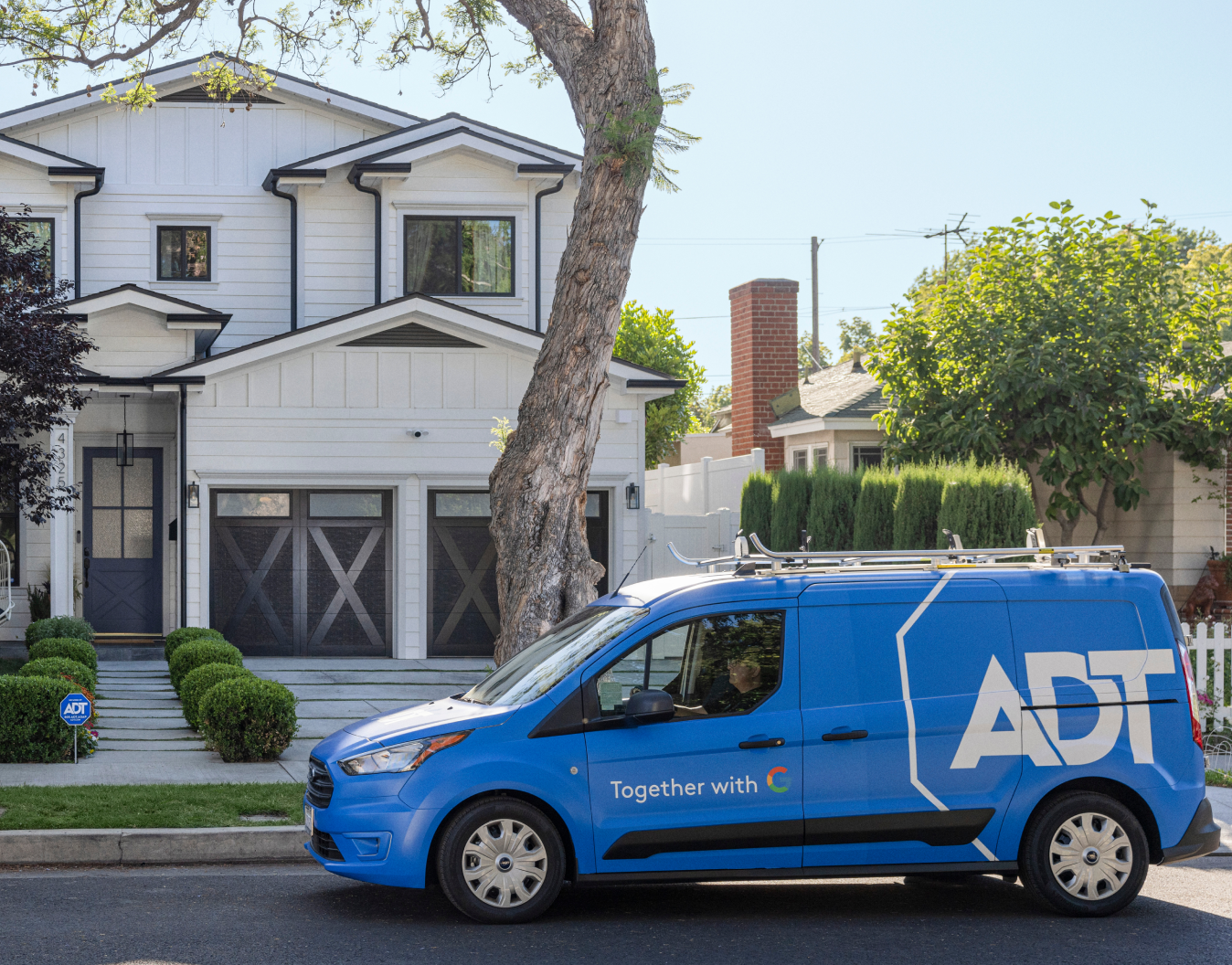 ADT van installer van parked outside of someone's house with a tree in front