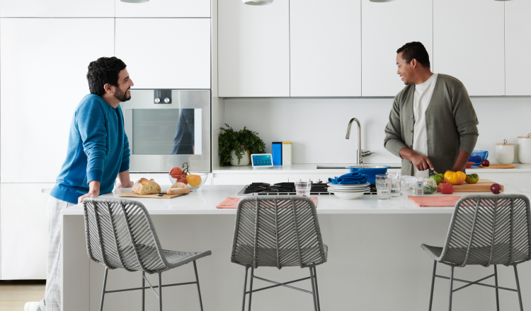 Two people at a kitchen table with Google device