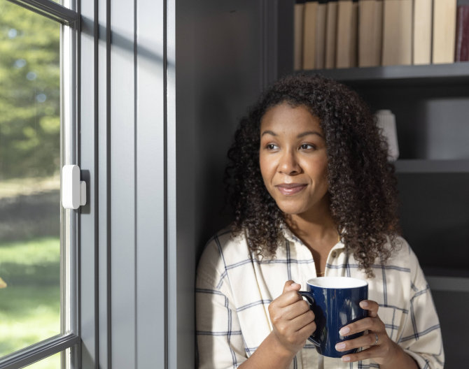 ADT customer standing next to her window that has a ADT Door/Window Sensor installed