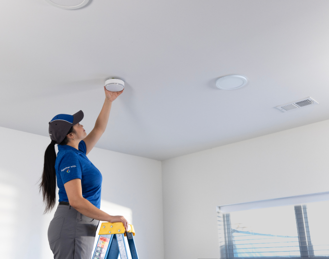 ADT installer installing a heat detector in someone's home