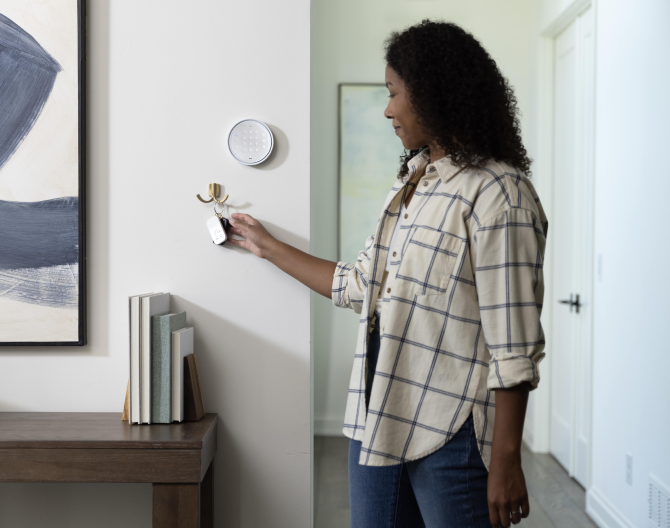 Woman hanging her house keys on a wall next to an ADT Keypad