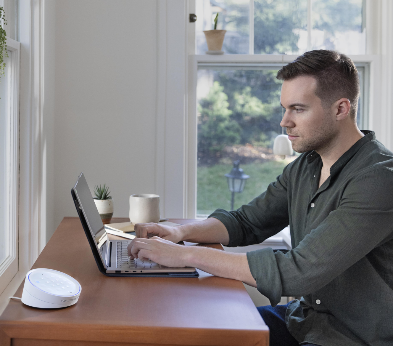 Man working on his laptop at a table with the ADT Keypad next to him