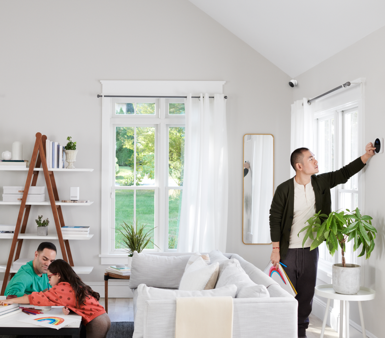 Family in the living room with a Google Nest Cam (outdoor or indoor, battery) in the background