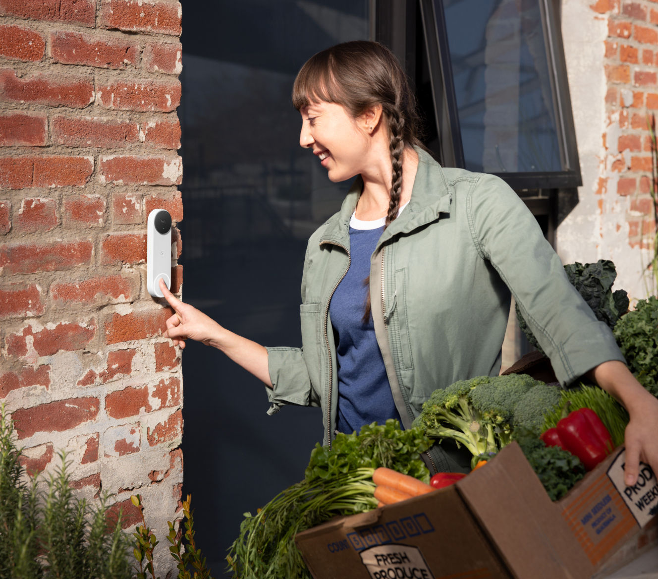 A delivery woman is ringing a Google Nest Doorbell(battery) standing in front of the door