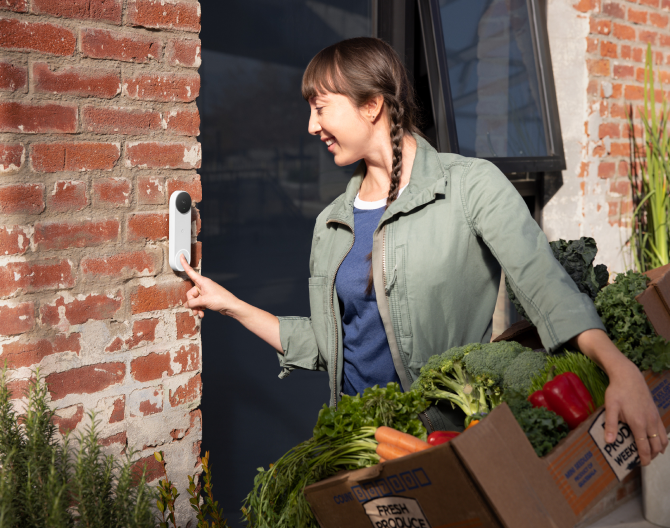 A delivery woman is ringing a Google Nest Doorbell(battery) standing in front of the door