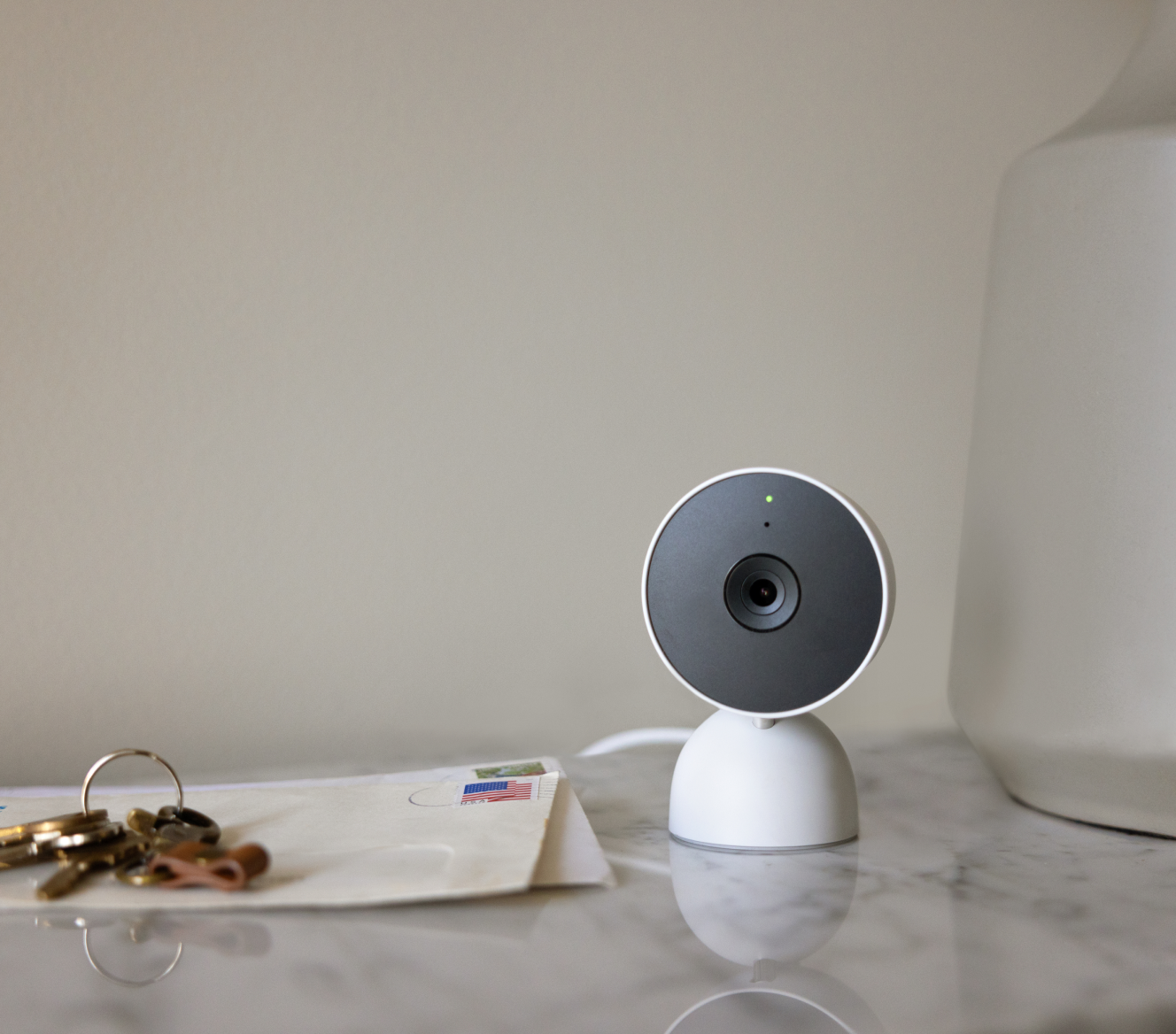 Google Nest Cam (indoor) on a table next to house keys and envelopes