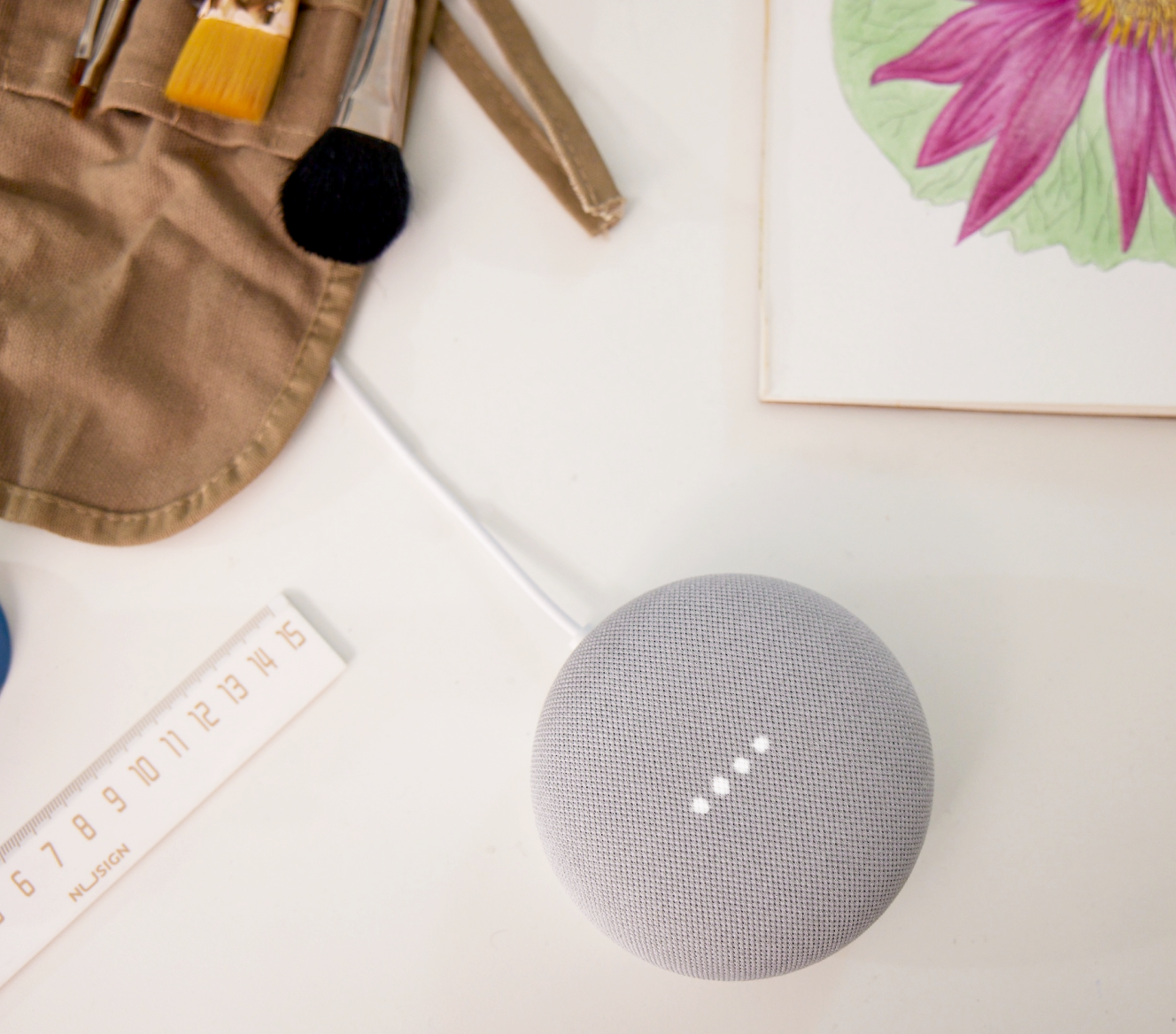 Google Nest Mini on a table with paint brushes and a ruler