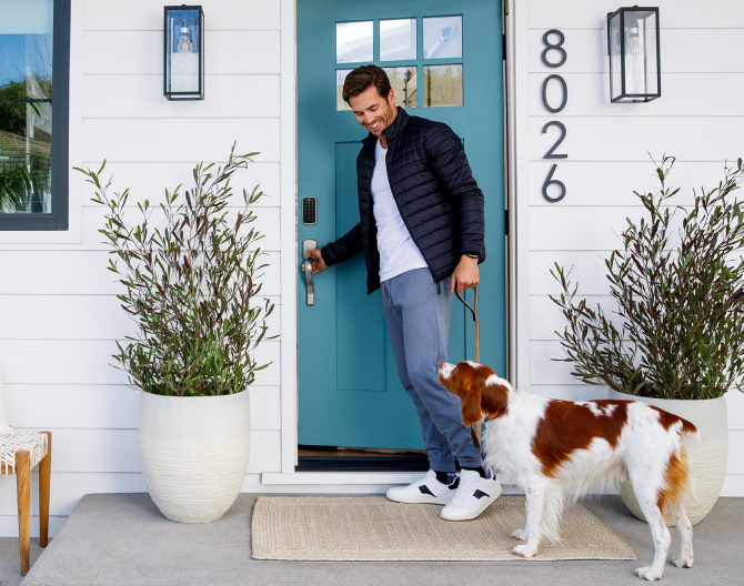 Homeowner with his dog outside of his front door that has a Yale Smart Lock on the door