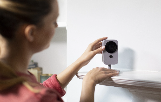 Woman self installing an ADT indoor camera on a shelf in her home